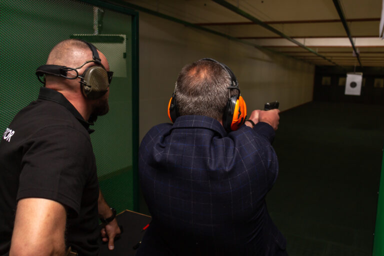 Shooting in the dash of short-barreled weapons. A man aims at a target before firing a pistol. The instructor in special ballistic headphones controls the process
